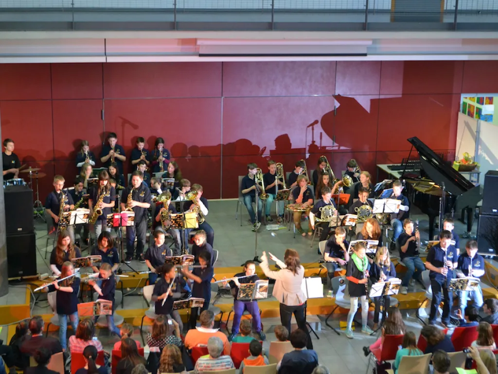 Ein Orchester spielt in der Pausenhalle, davor sitzt das Publikum.